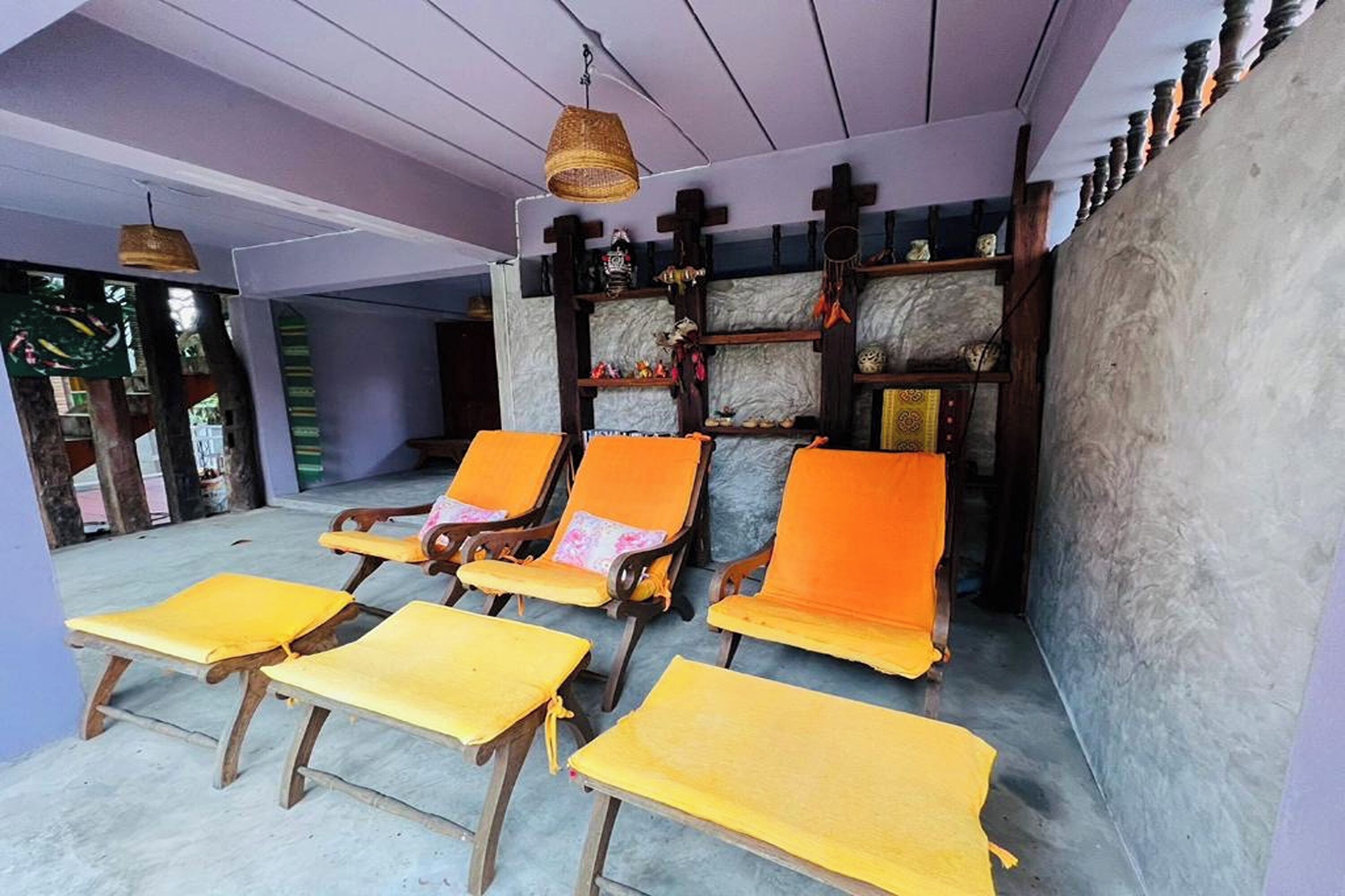 Een kamer met houten meubels, zoals stoelen en tafels, en een wand versierd met planken en decoratieve objecten.