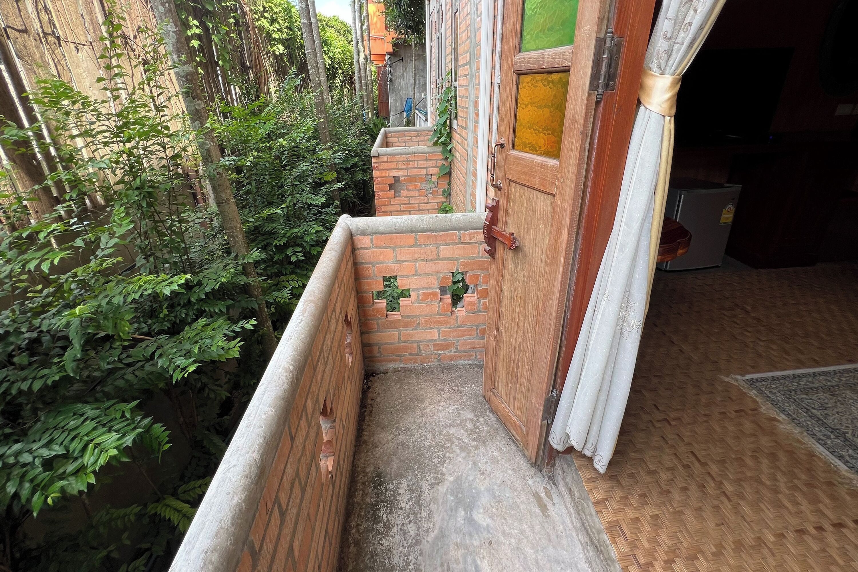 A narrow outdoor corridor with brick walls, a wooden door, and a small step leading to a higher level.