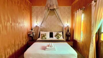 A neatly made bed with a canopy, two bedside tables with lamps, and patterned wallpaper.