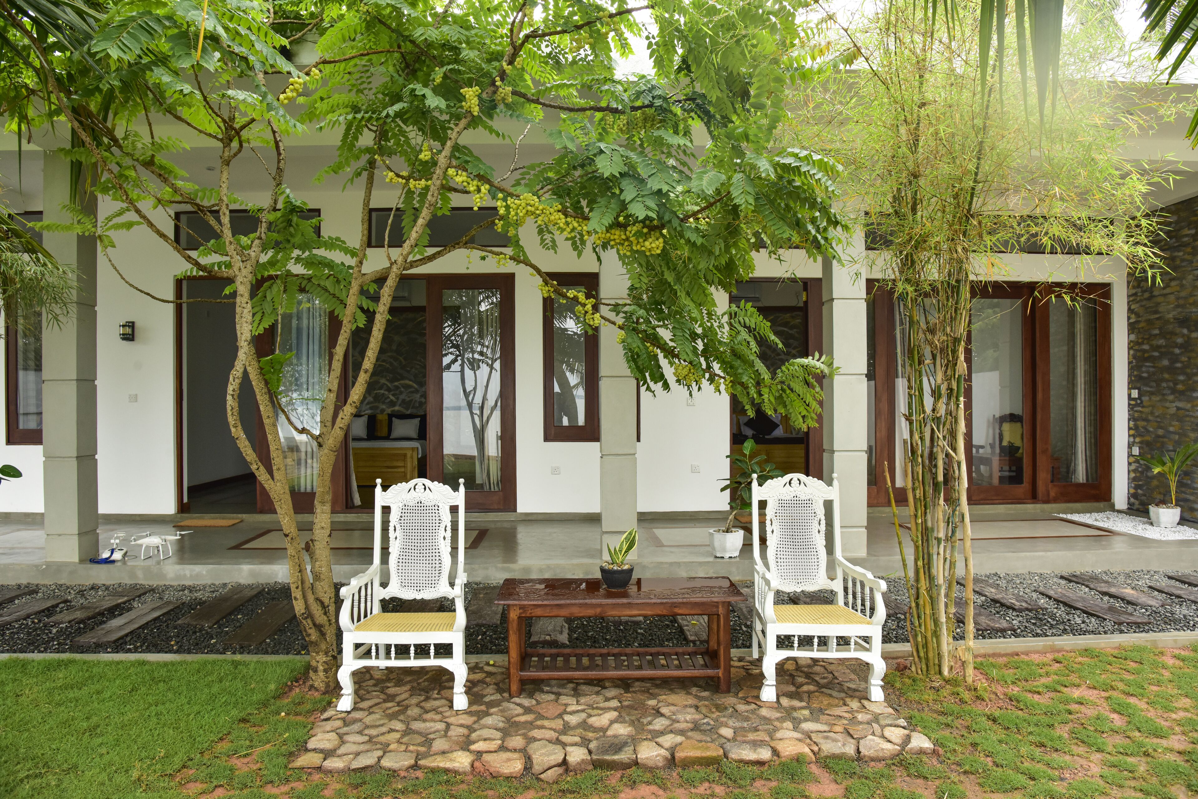 Un patio con dos sillas blancas, una mesa de madera y una planta en maceta.