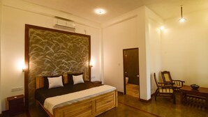 Une chambre à coucher avec un grand lit, une tête de lit en bois, des tables de chevet et un coin repas comprenant des chaises et une table.