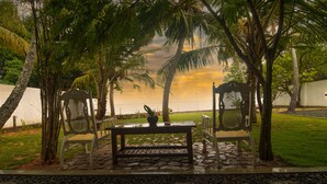 Une terrasse avec une table et deux chaises, entourée de palmiers et offrant une vue sur la plage.