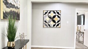 A spacious hallway with a black marble console table, a potted plant, and a geometric wall art piece. - Charming 3BR/2BA Near Galleria/NRG, Top Hospitals & LA Fitness (Houston)