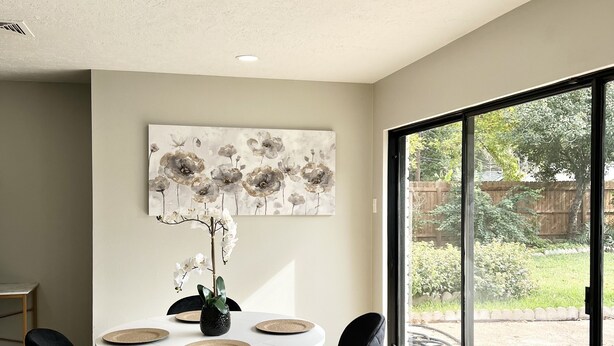 A dining area with a round table, black chairs, and a floral painting on the wall. - Charming 3BR/2BA Near Galleria/NRG, Top Hospitals & LA Fitness (Houston)
