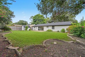 A residential property with a well-maintained lawn, a garage, and a small shed.