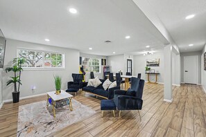 Un salon spacieux comprenant un ensemble de canapés, une table basse et un coin repas avec des chaises.