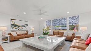 Ein geräumiges Wohnzimmer mit einem großen weißen Couchtisch, zwei braunen Ledersofas und einem Deckenventilator.