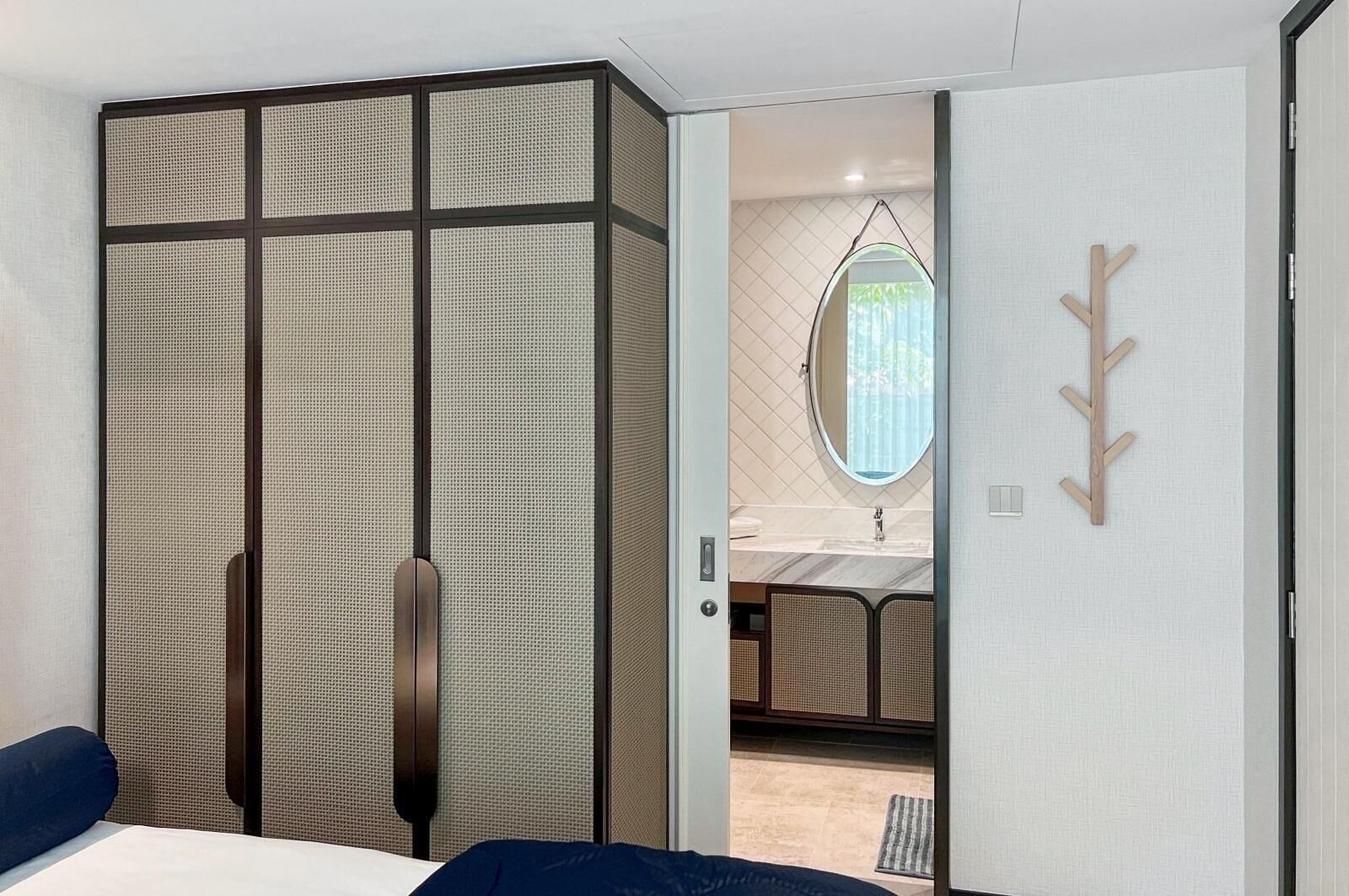 Ein Schlafzimmer mit einem großen Bett, einem Schrank mit Schiebetür, einem Spiegel und einem Holz-Kleiderständer.