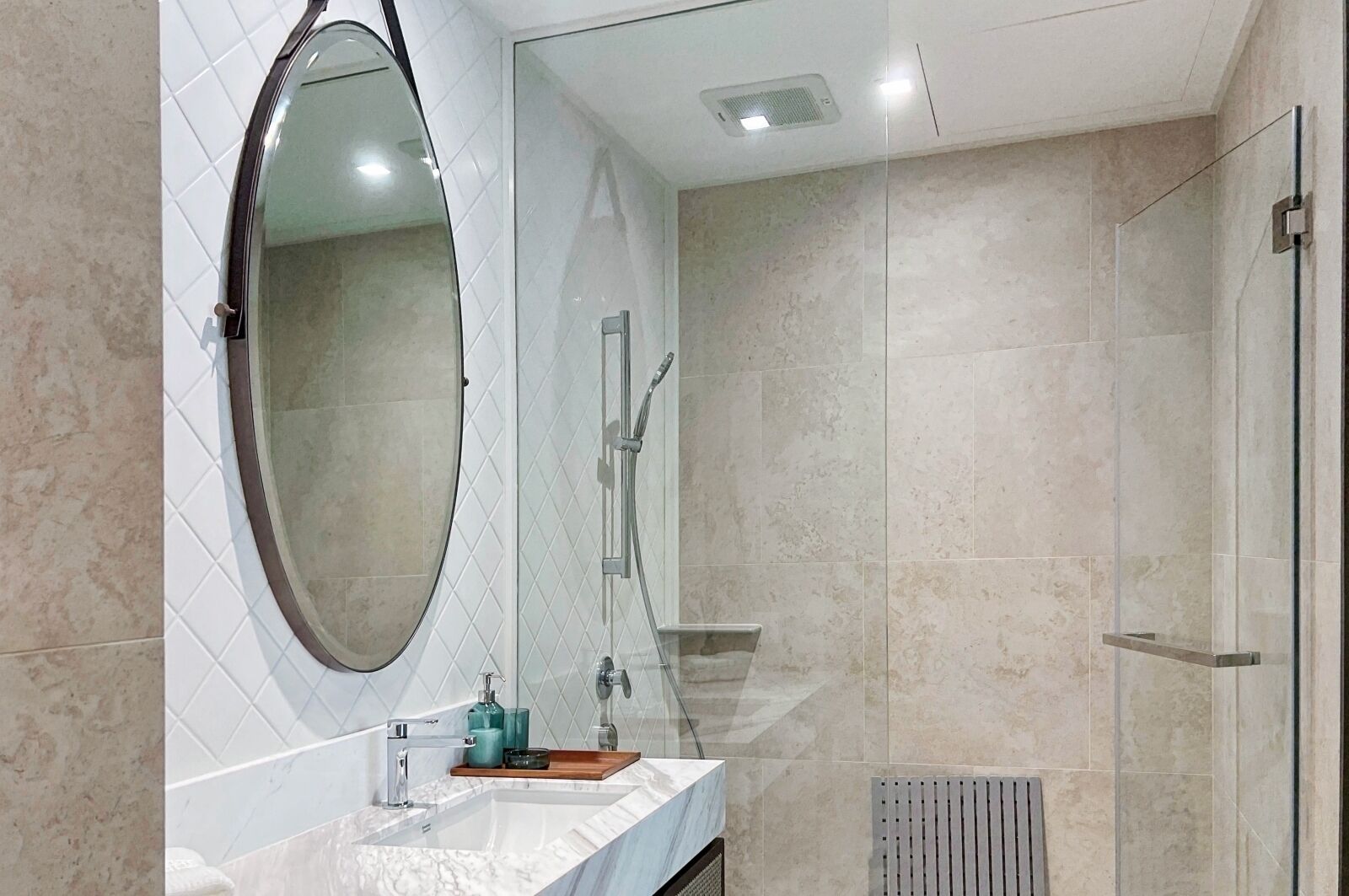 Un baño moderno con un espejo grande, ducha y lavamanos de mármol.