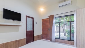 A room with a bed, a mounted TV, a window with curtains, and an air conditioning unit. - Asri Guesthouse (Aik Berik)