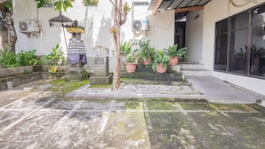 A courtyard with potted plants, a stone bench, and a statue. - Asri Guesthouse (Aik Berik)