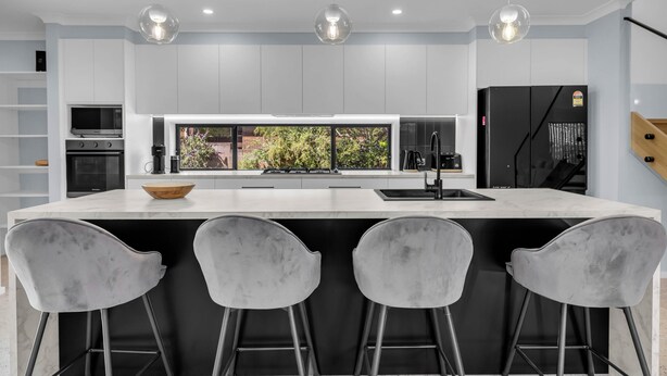 A modern kitchen with a large island, bar stools, and a view of greenery outside. - Heather - Pet Friendly Merimbula (Merimbula)