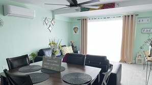 A modern living room with a dining area, featuring a ceiling fan, a sofa set, a coffee table, and decorative wall art. - SEAFLECTIONS - Relax, Reflect & Reminisce on the MUSIC, ART and CULTURE.  (Kingston)