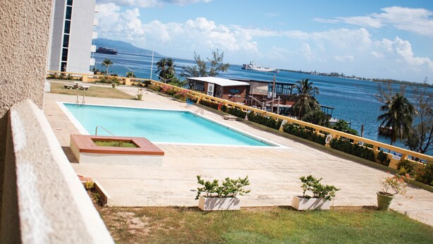 A swimming pool with a view of the ocean and a large ship in the distance. - SEAFLECTIONS - Relax, Reflect & Reminisce on the MUSIC, ART and CULTURE.  (Kingston)