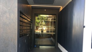 A modern building entrance with a glass door, a metal staircase, and a row of mailboxes on the left. - Mega Style Apartments - The Marc (St Kilda)