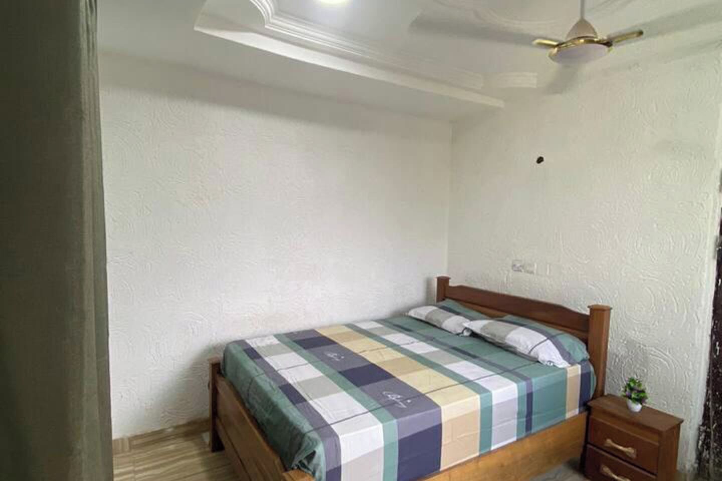 A bedroom with a wooden bed, a nightstand, and a ceiling fan.