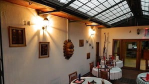 Un restaurante con mesas redondas, sillas de madera y un alto techo con tragaluz.