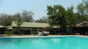 Una piscina con superficie de agua azul cristalina, rodeada de edificios con techos verdes y árboles.