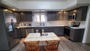 A modern kitchen with dark cabinets, a stainless steel refrigerator, a microwave, and a dining table with chairs. - Grandote Lodge (La Veta)