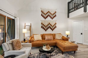 A modern living room with a sectional sofa, a side table, and a coffee table. There are two wall-mounted macramé wall hangings above the sofa. - Hot Tub, Skiing 2 Min Away, Cozy Modern Condo! (Durango)