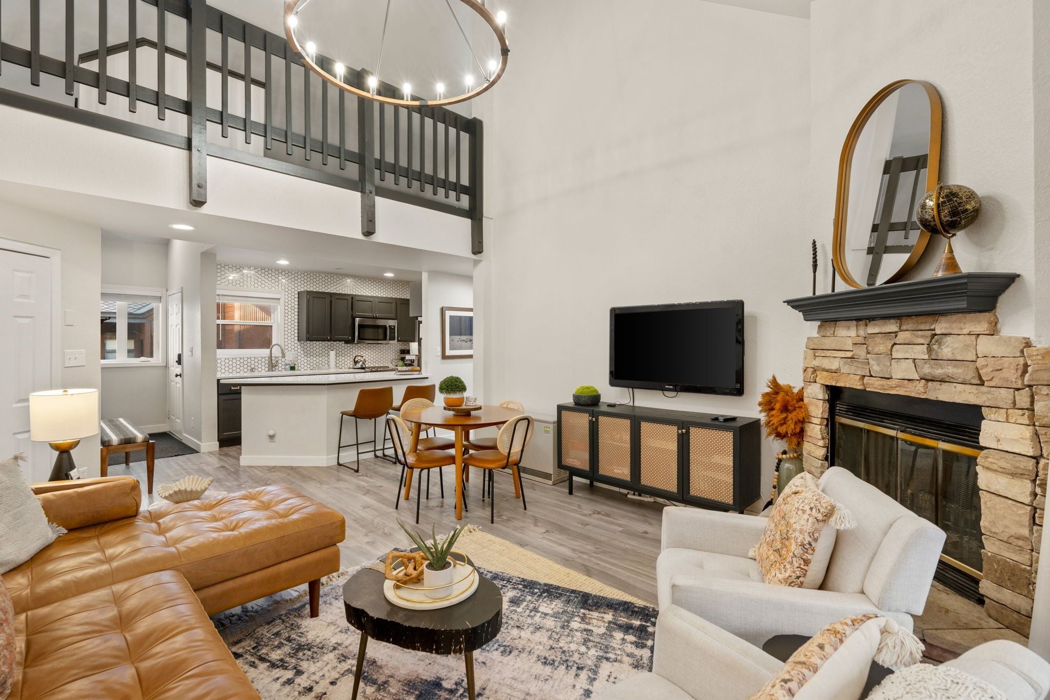 A modern living room with a fireplace, a dining area, and a kitchen in the background.