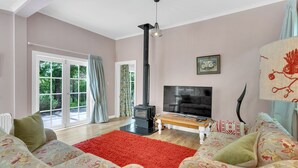 A living room with a sofa, a red rug, a TV, a black heater, and a window with curtains.