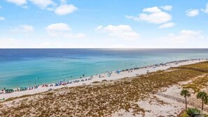 Een strand met een lange zandvlakte, een heldere blauwe lucht en een kalme zee.