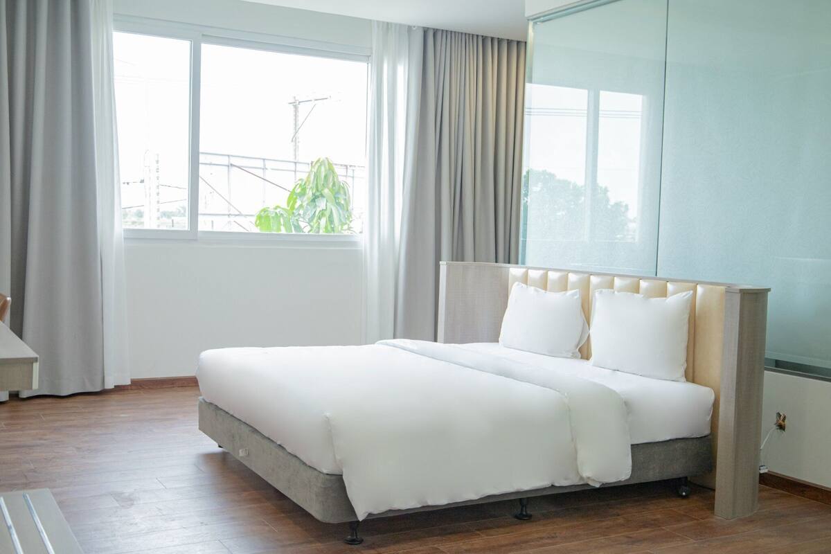 Une chambre moderne avec un grand lit, une vue sur l’extérieur et une fenêtre avec des rideaux.