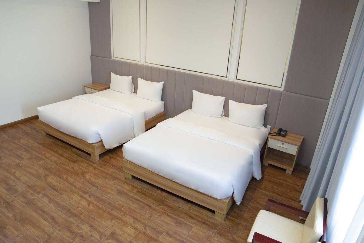 Une chambre d’hôtel avec deux lits, un plancher en bois et une table de chevet avec un téléphone.
