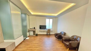 Un salon moderne avec un plancher en bois, un canapé, un téléviseur et un petit bureau avec une chaise.