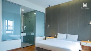 Une chambre d’hôtel moderne avec un grand lit, une douche à parois de verre et un plancher en bois.