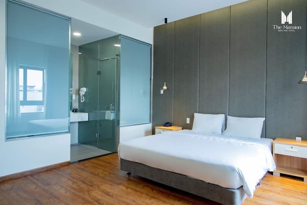 Une chambre d’hôtel moderne avec un grand lit, une douche à parois de verre et un plancher en bois.