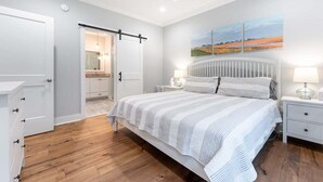 A bedroom with a bed, bedside tables, a ceiling fan, and a painting on the wall. - Luxury St. Simons Island Vacation Rental | Private Pool Near Pier Village (Saint Simons Island)