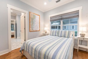 Quarto com uma cama, um mapa na parede, janela com persianas e mesa de cabeceira com abajur.