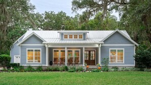 A two-story house with a front porch, a garage, and a well-maintained lawn. - Luxury St. Simons Island Vacation Rental | Private Pool Near Pier Village (Saint Simons Island)