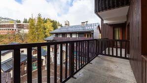 Un balcon avec vue sur une montagne et sur des arbres aux couleurs automnales.