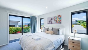 A modern hotel room with a large bed, a nightstand, and a window with a view of the outdoors. - Sunset Peaks Wanaka T (Wānaka)