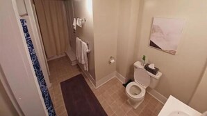 A bathroom with a toilet, a sink, and a shower area.