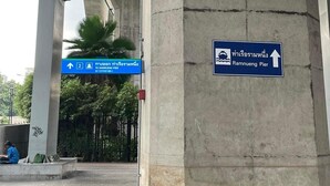 A concrete pillar with directional signs for Ramnueng Pier and a blue sign with a water wave symbol.