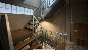 A modern staircase with metal railings and wooden steps, leading to a higher floor.