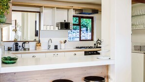Une cuisine moderne dotée d’un îlot central, d’un four à micro-ondes, d’un évier et d’une fenêtre donnant sur un paysage verdoyant.