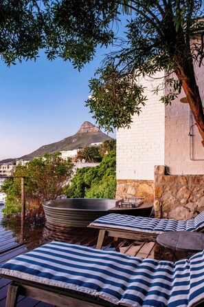 A terrace with a view of a mountain, a stone wall, and a white building.