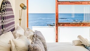 Une chambre avec un grand lit, une vue sur la mer et une fenêtre à cadre en bois.