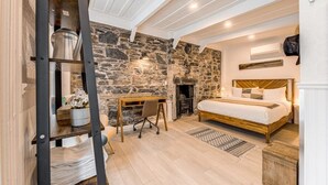 Ein Schlafzimmer mit Steinsandsteinwand, einem hölzernen Bett, einem Schreibtisch und einer Himmelsleiter.