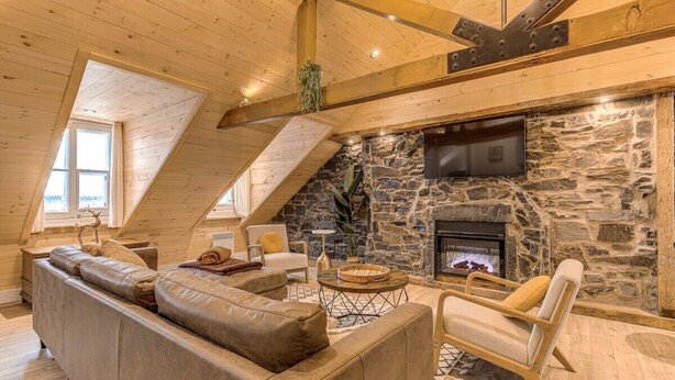Ein gemütliches Wohnzimmer mit Kamin aus Stein, Holzbalken und einer bequemen Sitzecke.