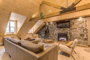 Un salon chaleureux avec une cheminée en pierre, des poutres en bois et un coin salon confortable.