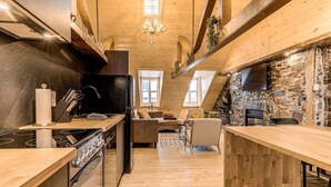 Eine moderne Küche mit Steinwand, Holzbalken und Kamin.