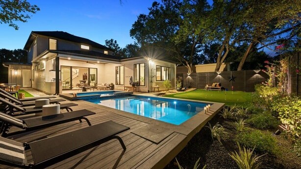Una casa moderna con piscina, sdraio e un giardino curato.