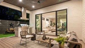 Patio esterno con barbecue, zona salotto e vista sull'interno dell'abitazione.