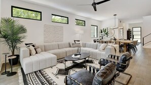Un soggiorno moderno con un divano componibile, un tavolino da caffè e un'area pranzo con sedie.